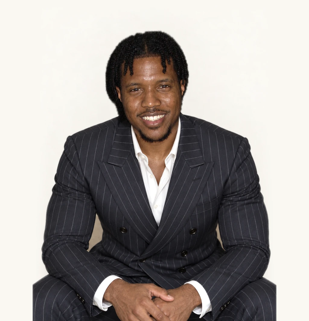 LaDonte Prince, seated, leaning forward, hands together, smiling.
