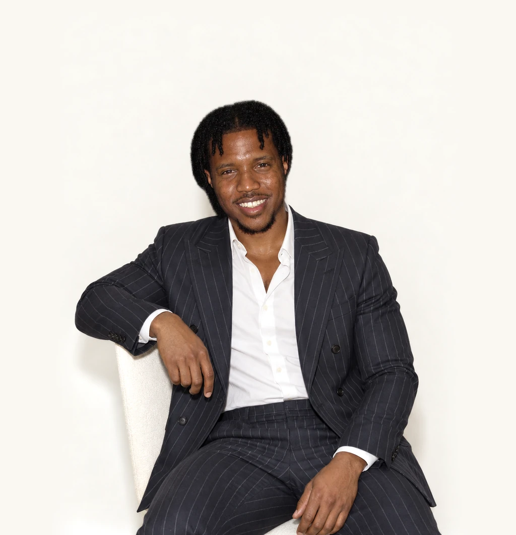 LaDonte Prince, seated, leaning on one forearm, smiling.